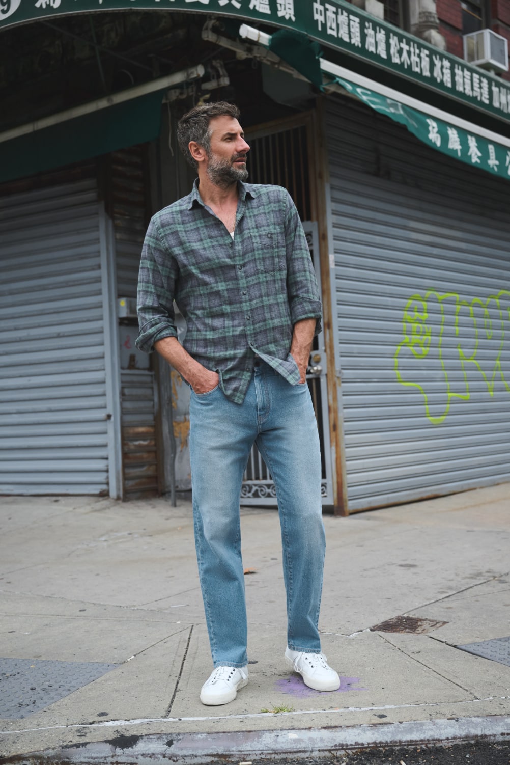 Man wearing casual flannel shirt in NYC, with hands in pocket