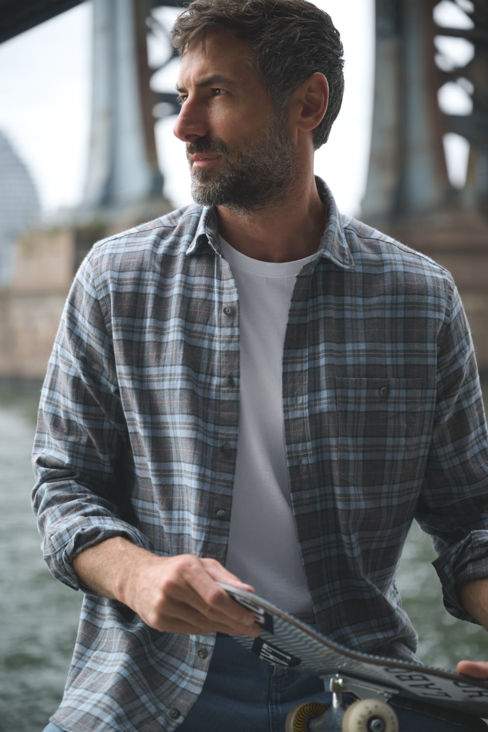 Man under bridge wearing casual flannel shirt