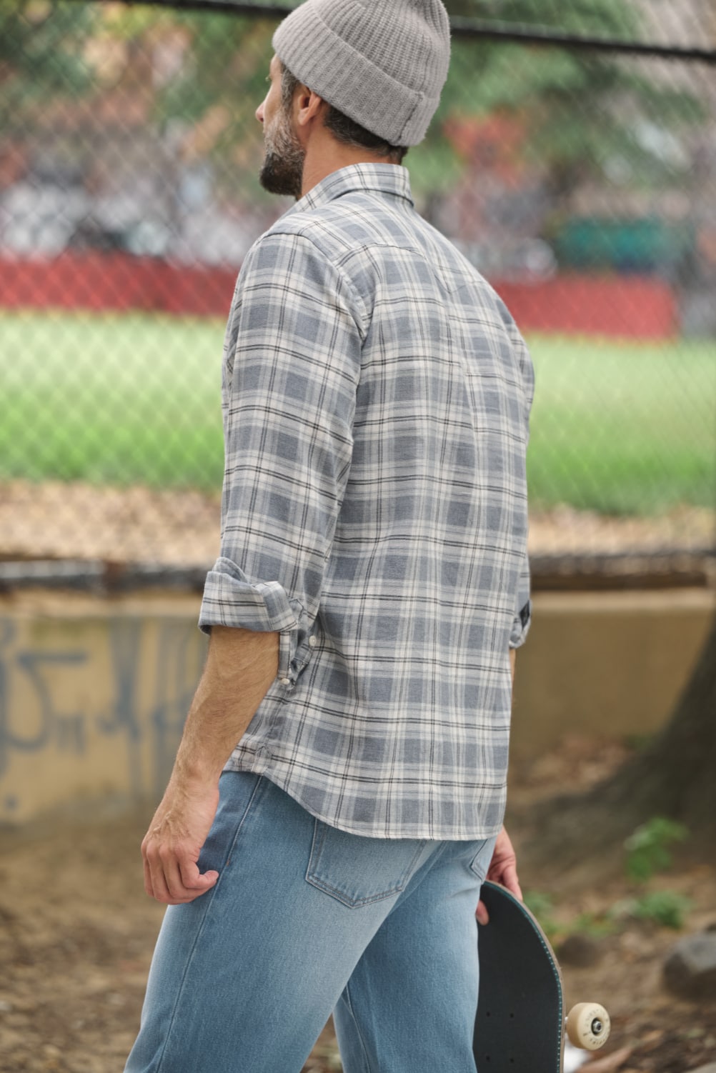 Man holding skateboard looking into the distance