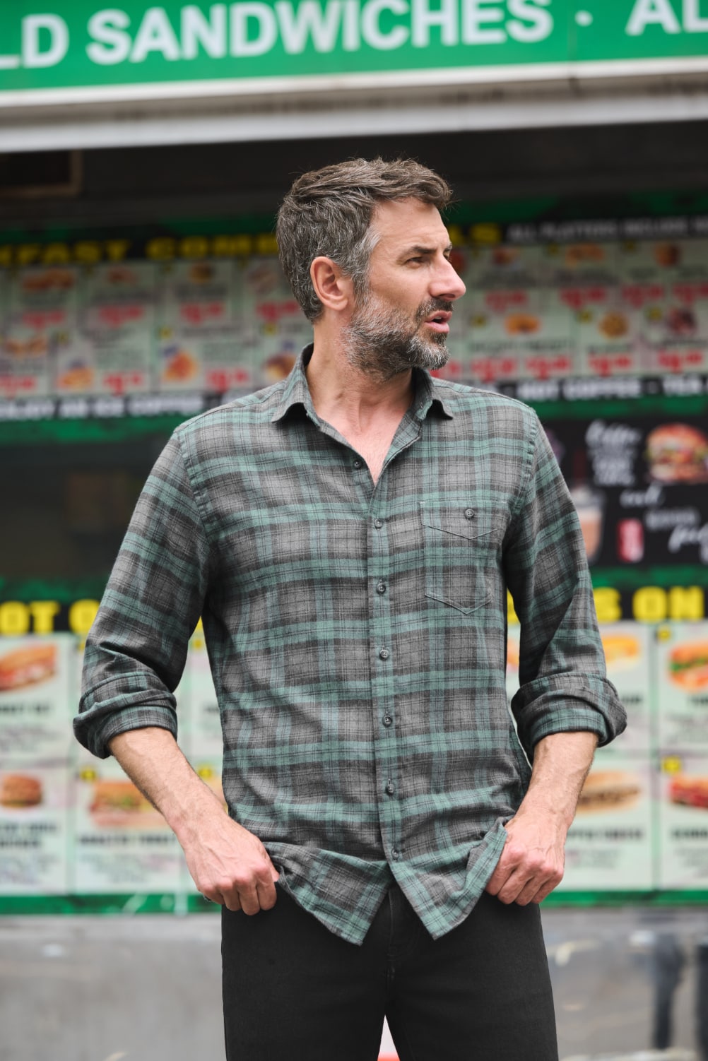 Man in front of bodega modeling a sage and charcoal shirt