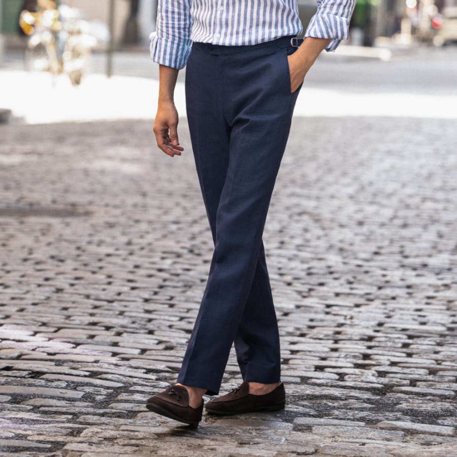 Man wearing custom linen dress pants, walking on a road.