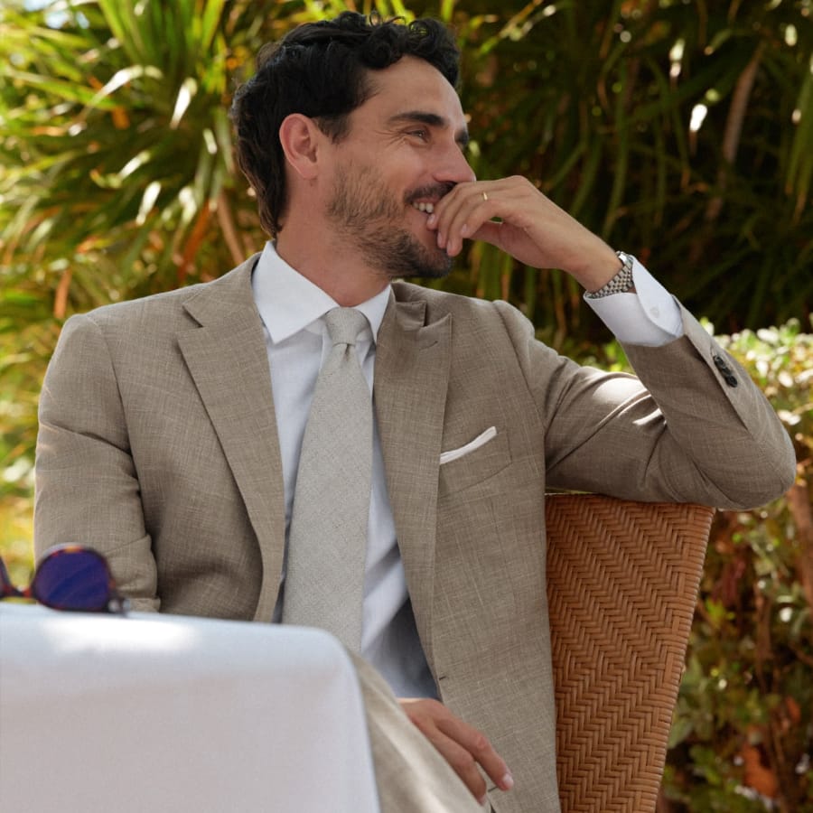Man wearing suit, sitting at a summer wedding party.