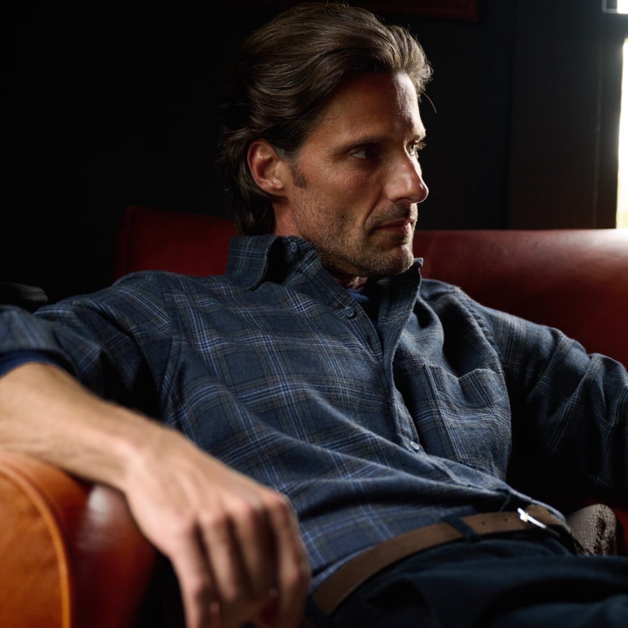 Man wearing a plaid flannel shirt sitting on a leather chair