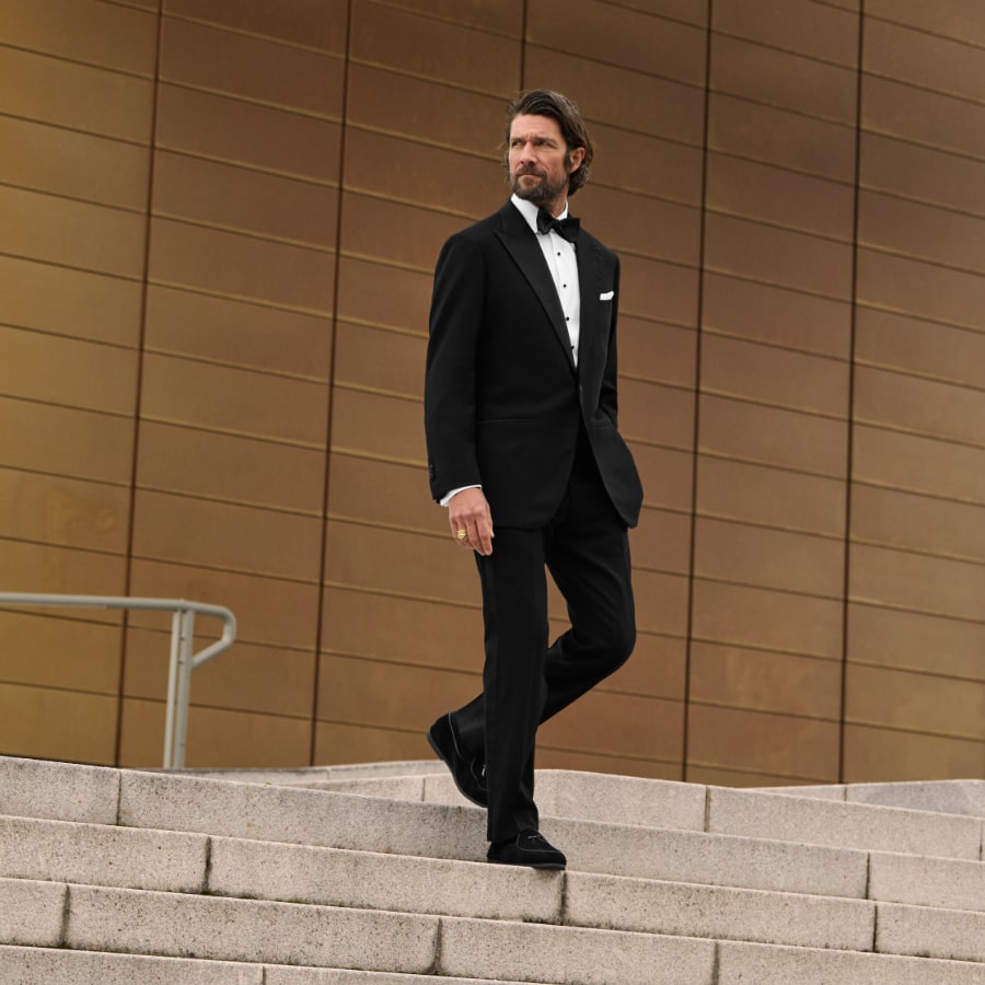 Man wearing custom tuxedo on stairs.