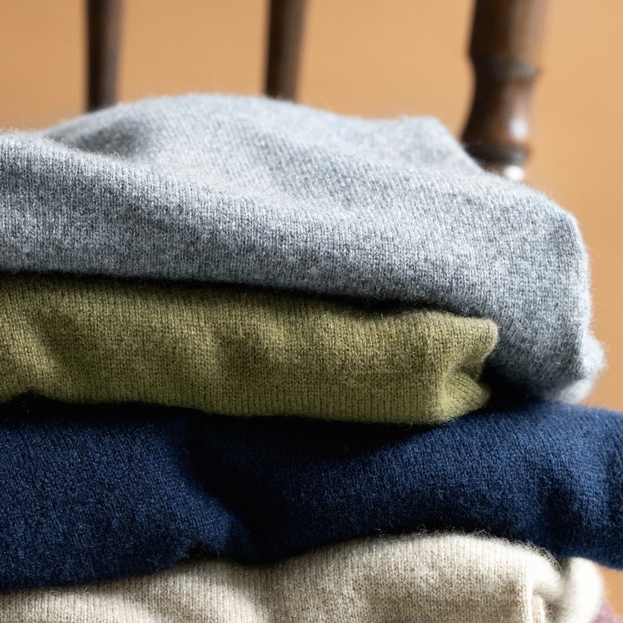 Stack of soft, colorful cashmere sweaters on a chair.