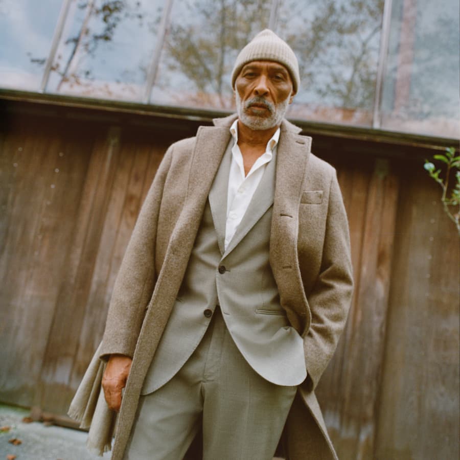 Man wearing suit and overcoat outside in rustic settings