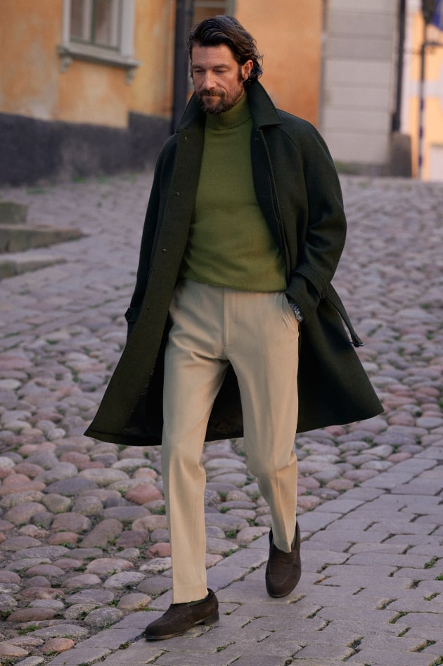 Man wearing flannel overcoat, standing on a stone street