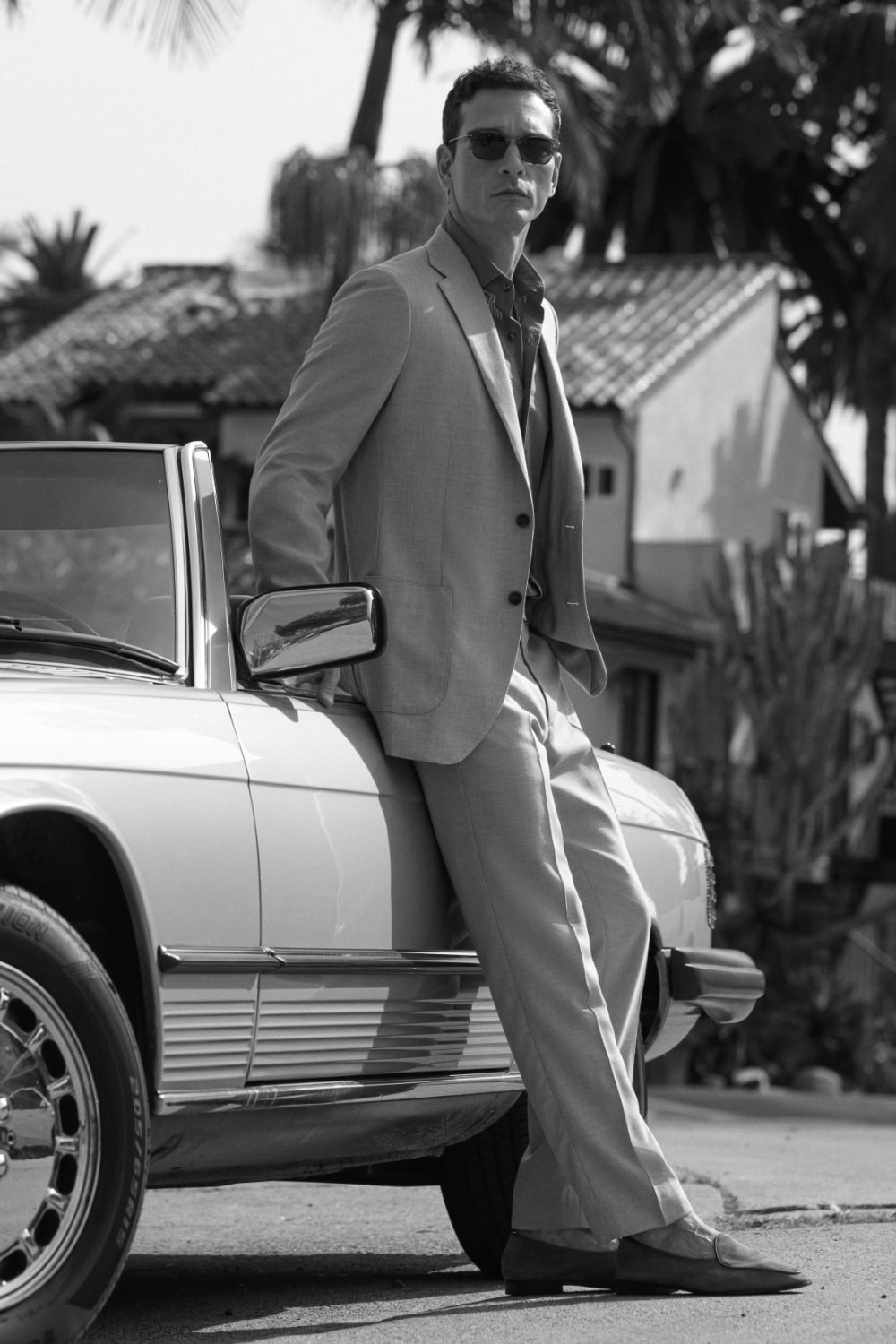 Man wearing a suit next to a classic car.
