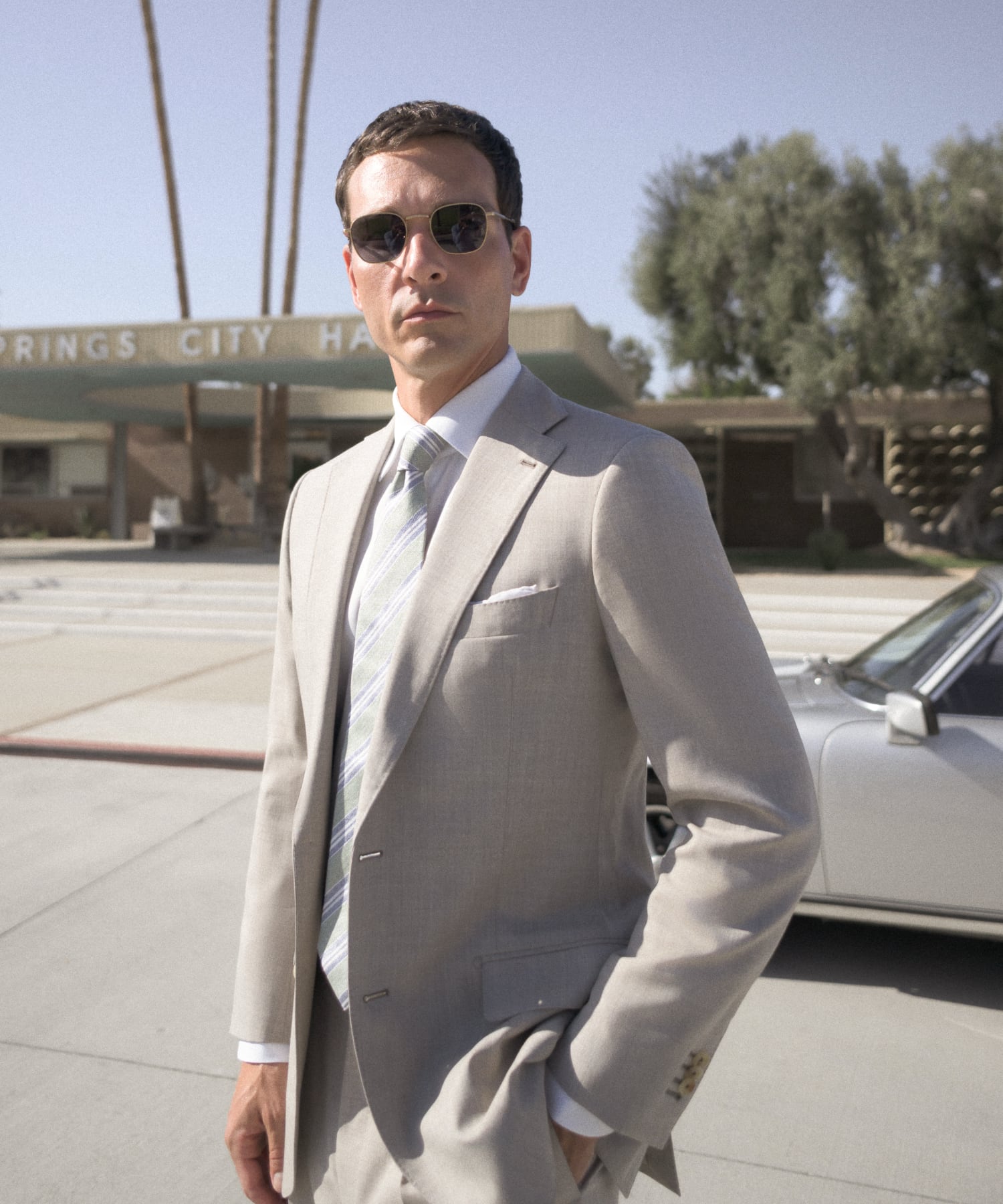 Man wearing a summer, linen suit, standing next to vintage car